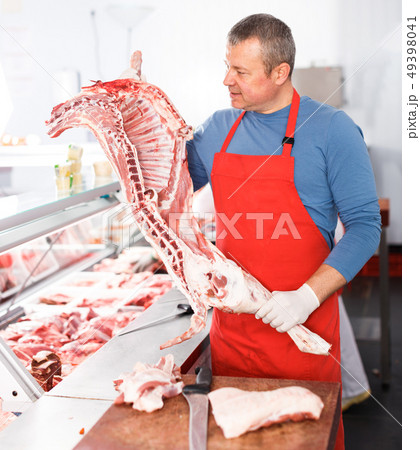 Adult man splitting and showing of pig carcass Adult man splitting and showing of pig carcass 49398041