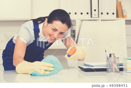Portrait of adult female cleaning office table Portrait of adult female cleaning office table 49398451