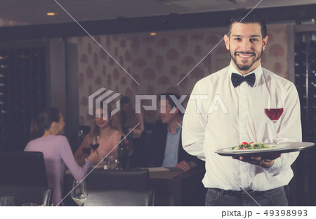 Adult waiter with tray welcoming to restaurant Adult waiter with tray welcoming to restaurant 49398993