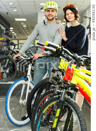 Young couple in helmet standing near bicycle Young couple in helmet standing near bicycle 49399130