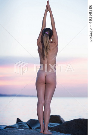 Young naked female practising yoga poses at seaside Young naked female practising yoga poses at seaside 49399286