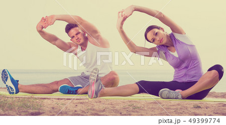 Couple doing yoga poses sitting on sea beach 49399774