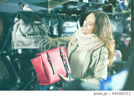 Excited female selecting new hand bag in shop Excited female selecting new hand bag in shop 49400251