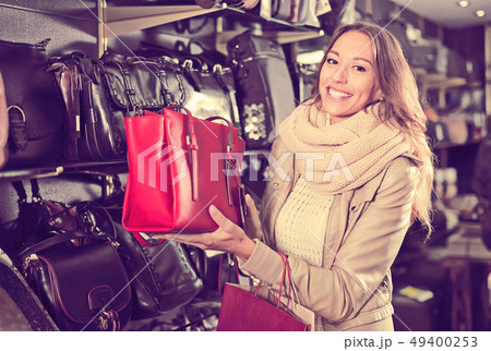 friendly woman buying leather purse in shop 49400253