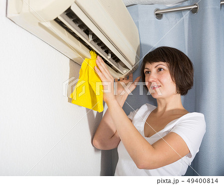 Woman dusting air conditioning Woman dusting air conditioning 49400814