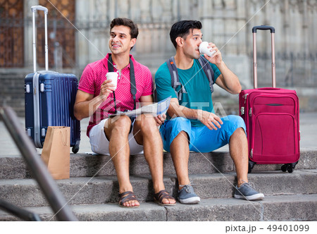 Men tourists are sitting with coffee and watching in map 49401099
