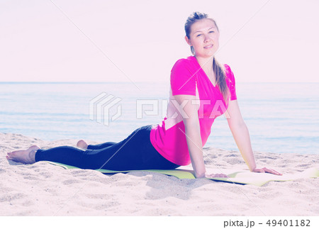 Woman exercising yoga poses on beach Woman exercising yoga poses on beach 49401182