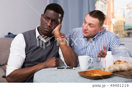 Two sad interracial men sitting at table after conflict 49401219