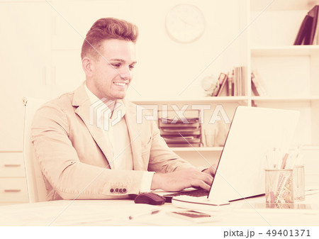 Smiling manager at office desk with laptop. 49401371