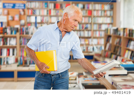 elderly man customer visiting bookshop in search of interesting fiction elderly man customer visiting bookshop in search of interesting fiction 49401419