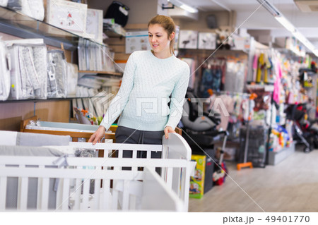 Smiling pregnant woman is choosing new crib for baby Smiling pregnant woman is choosing new crib for baby 49401770