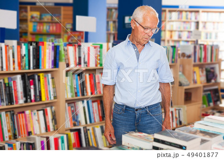 Older man choosing books in bookstore Older man choosing books in bookstore 49401877
