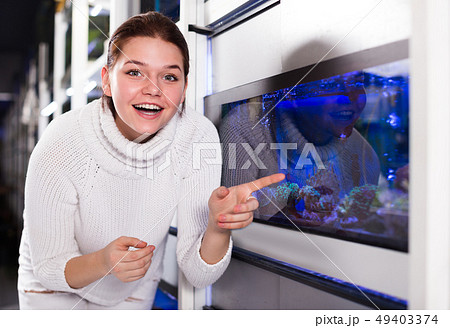 Girl near big aquarium is pointing to interesting model of aquariums 49403374