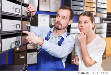 Male worker helping young client woman choosing new mailbox Male worker helping young client woman choosing new mailbox 49403386