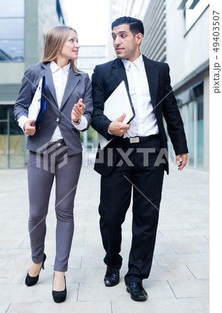 Businesswoman and her partner are going to office and talking about project 49403507