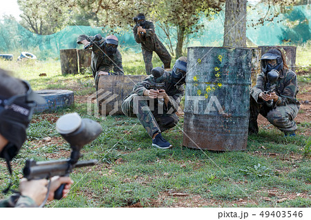 Two opposing groups shooting on paintball playing field outdoors 49403546