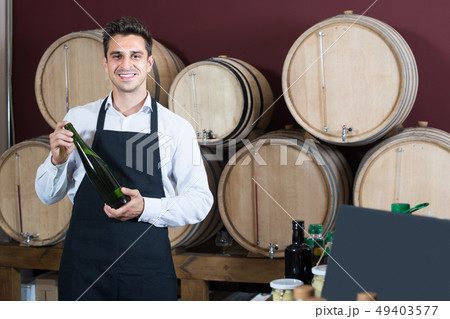 seller in apron holding bottle of wine. seller in apron holding bottle of wine. 49403577
