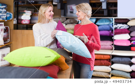 young and senior female customers looking through pillows in textile shop young and senior female customers looking through pillows in textile shop 49403734