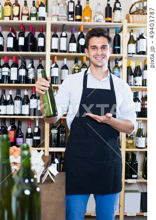 man seller holding bottle of wine in shop . man seller holding bottle of wine in shop . 49403787