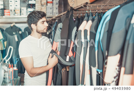 man holding and choosing suit for surfing in the shop man holding and choosing suit for surfing in the shop 49403980