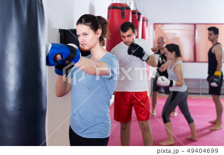 young sportswoman in the boxing hall practicing boxing punches with boxing bag young sportswoman in the boxing hall practicing boxing punches with boxing bag 49404699