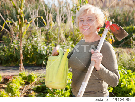Senior woman with watering can in garden 49404986