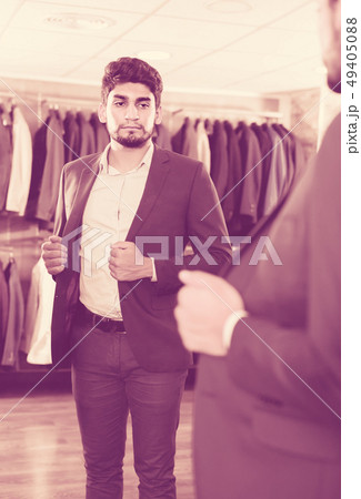 Young visitor is trying on jacket in front of the mirror 49405088