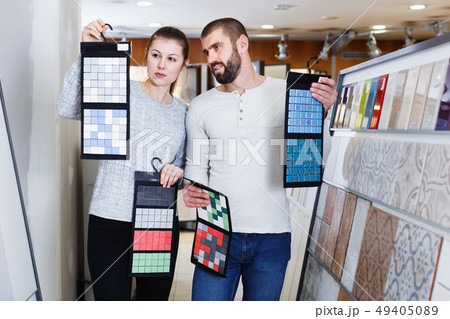 Positive couple holding sample of kitchen ceramic tile in modern store 49405089