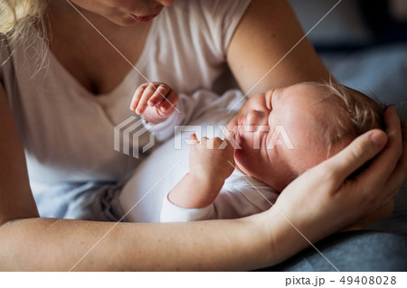 A midsection of mother with a sleeping newborn baby at home. A midsection of mother with a sleeping newborn baby at home. 49408028