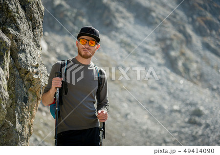 Porter of a stylish hipster traveler with a beard and a backpack in sunglasses and a cap with Porter of a stylish hipster traveler with a beard and a backpack in sunglasses and a cap with 49414090