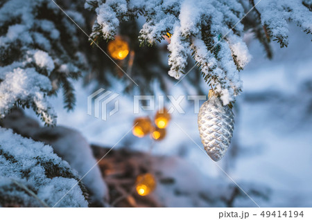 Close-up of a Christmas toy on a snow-covered lively tree in the winter forest on the background of 49414194