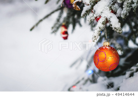 Close-up of a Christmas toy on a snow-covered lively tree in the winter forest on the background of Close-up of a Christmas toy on a snow-covered lively tree in the winter forest on the background of 49414644