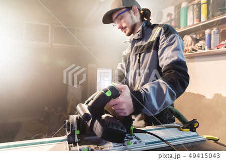Portrait of a young carpenter joiner with manual circular power saw in the hands of a worker in a 49415043