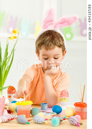 little child boy with Easter bunny ears painting Easter eggs little child boy with Easter bunny ears painting Easter eggs 49416589