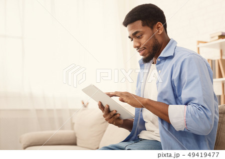 Young african american man using digital tablet Young african american man using digital tablet 49419477