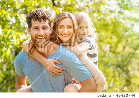 Strong man supporting his family by carrying wife and son piggyback 49420744