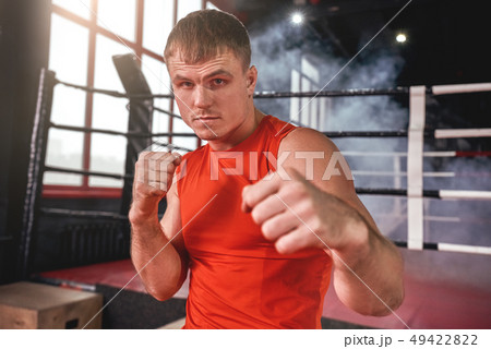 Perfect boxing stance. Close-up of focused muscular boxer in sports clothing looking at camera while Perfect boxing stance. Close-up of focused muscular boxer in sports clothing looking at camera while 49422822