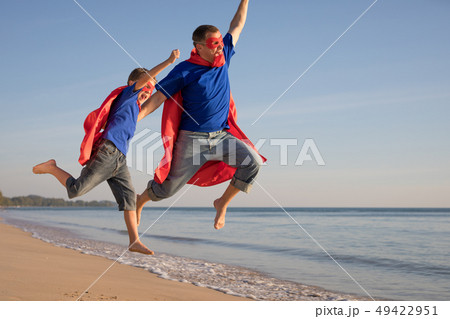 Father and son playing superhero on the beach at 49422951