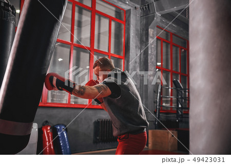 Way of life. Muscular sportsman in sports clothing exercising on heavy punch bag before fight in Way of life. Muscular sportsman in sports clothing exercising on heavy punch bag before fight in 49423031