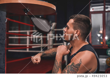 Ready to break his record. Close-up of muscular tattooed boxer in sports clothing hitting punching Ready to break his record. Close-up of muscular tattooed boxer in sports clothing hitting punching 49423053