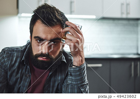 Either you run the day, or the day runs you. Front view of drunk man with glass of whiskey, sitting Either you run the day, or the day runs you. Front view of drunk man with glass of whiskey, sitting 49423602