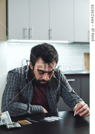 The dead drug leaves a ghost behind. At certain hours it haunts the house. Man preparing to snort a The dead drug leaves a ghost behind. At certain hours it haunts the house. Man preparing to snort a 49423639