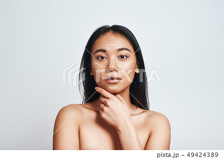 Perfect skin. Portrait of beautiful asian woman touching her skin and looking at camera while 49424389