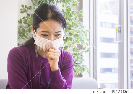 マスクをして口に手を当てる女性 花粉症 風邪の写真素材