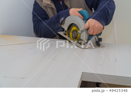 Carpenter using a saw to cut laminate counter top. Carpenter using a saw to cut laminate counter top. 49425346