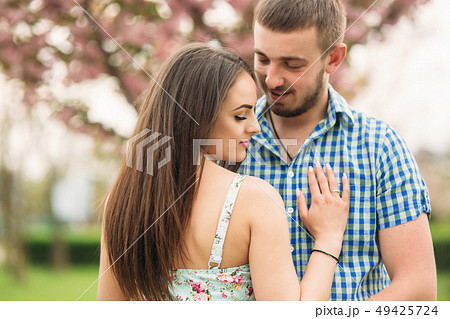 Portrait of young couple in spring mood. Blooming trees around man and woman 49425724