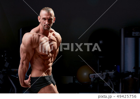 Athletic man posing. Photo of man with perfect physique on black background. Strength and motivation Athletic man posing. Photo of man with perfect physique on black background. Strength and motivation 49425756