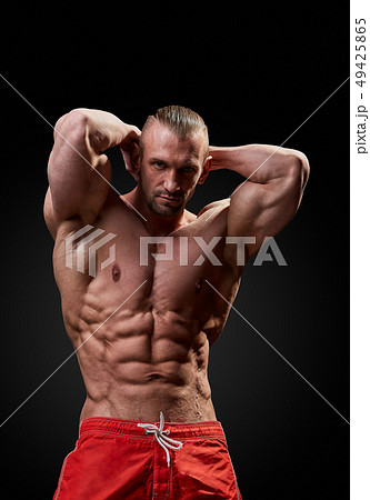 Athletic man posing. Photo of man with perfect physique on black background. Strength and motivation Athletic man posing. Photo of man with perfect physique on black background. Strength and motivation 49425865