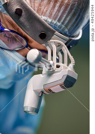 Close up portrait of female surgeon doctor wearing protective mask and hat during the operation 49425944