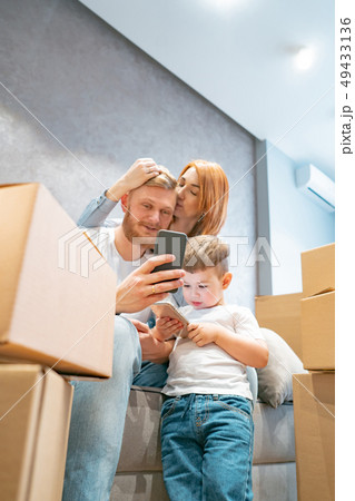 Young happy family with kid unpacking boxes together sitting on sofa Young happy family with kid unpacking boxes together sitting on sofa 49433136